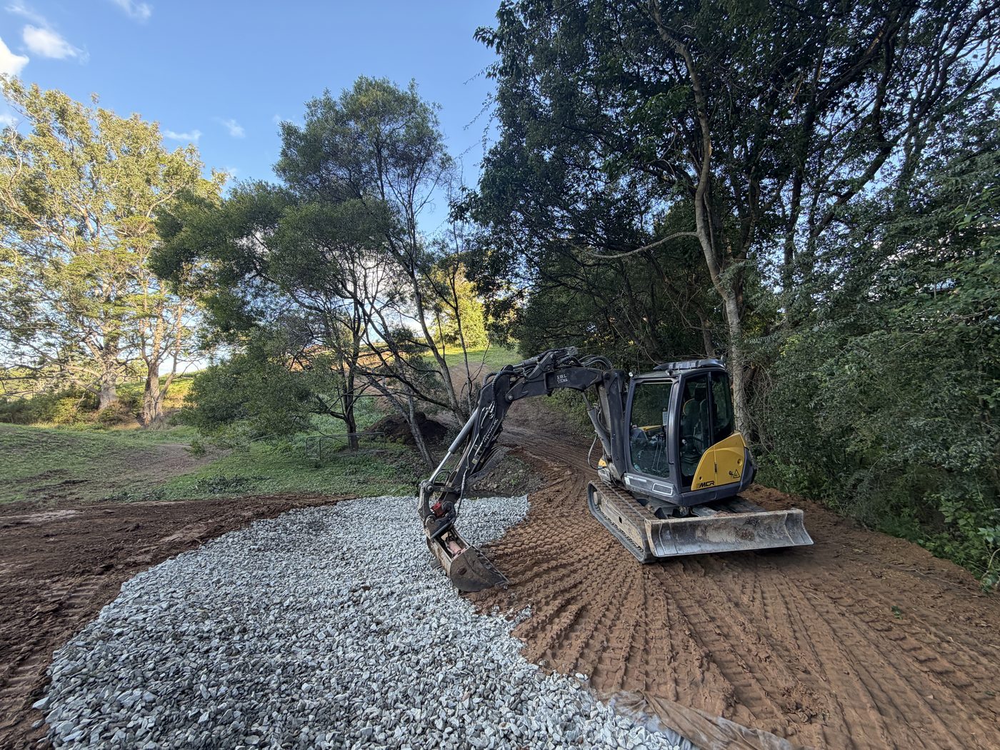 Mecalac 6MCR spreading gravel on a curving tree-lined driveway, Yarraman Rd Sawtell