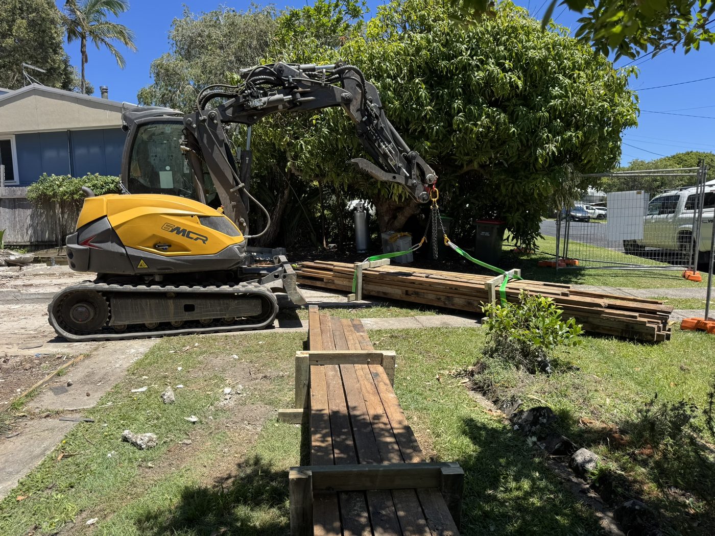Mecalac 6MCR chain-lifting salvaged timber during a site clear at Dillon St Sawtell